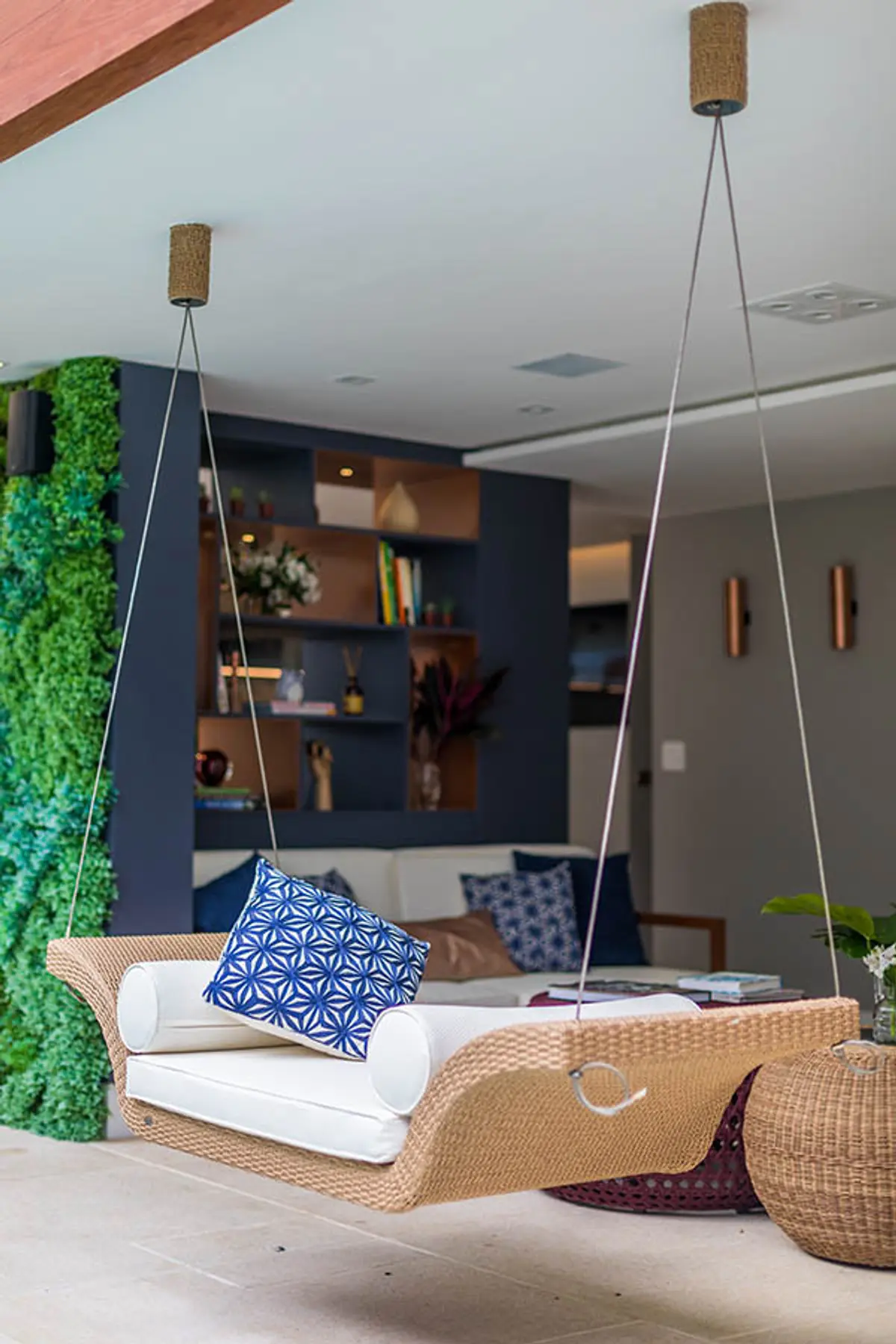 Terraza moderna con sofá de ratán suspendido y jardín vertical integrado — proyecto Casa Barra ED, por Amanda Miranda