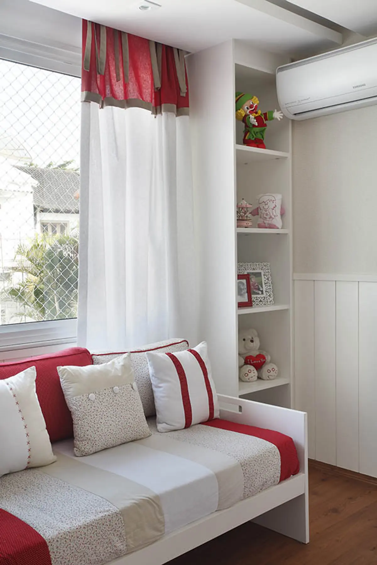 Dormitorio luminoso con cama tapizada, estantes y cortinas rojas blancas — proyecto Casa Barra ED, por Amanda Miranda