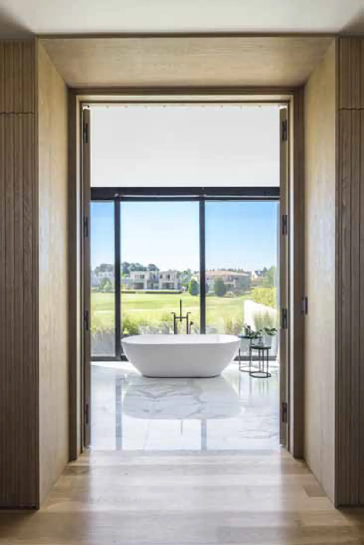 Baño moderno con bañera exenta y vistas panorámicas a campo de golf — proyecto Pilará, por Martin Gomez, en Pilará