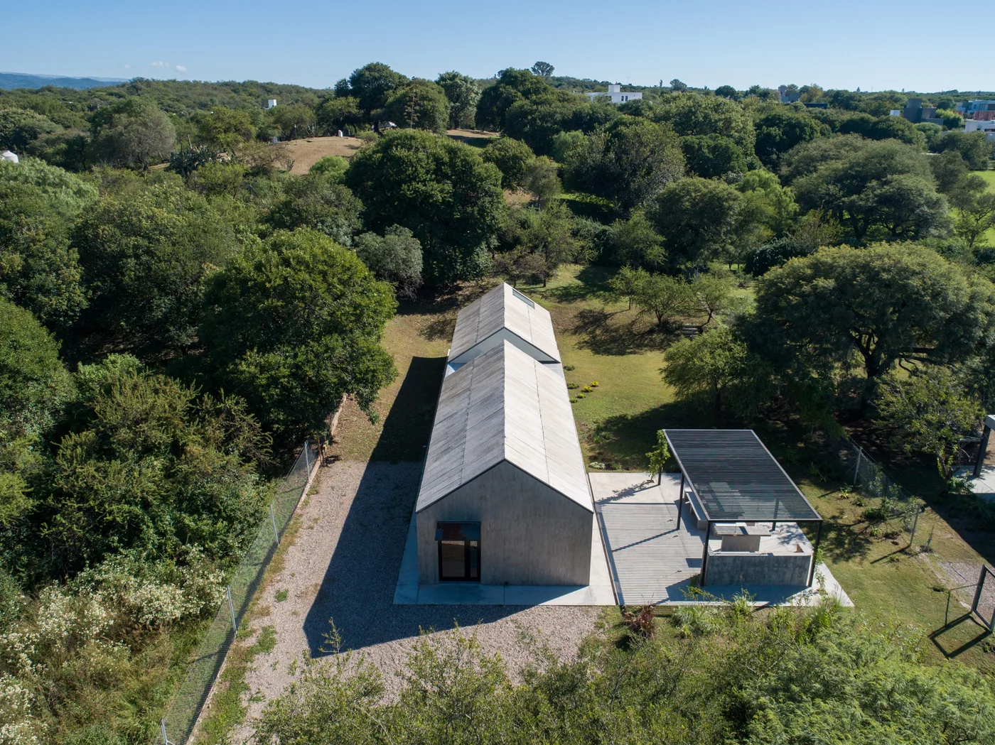 Casa contemporánea con fachada de hormigón en paisaje rural rodeada de vegetación.