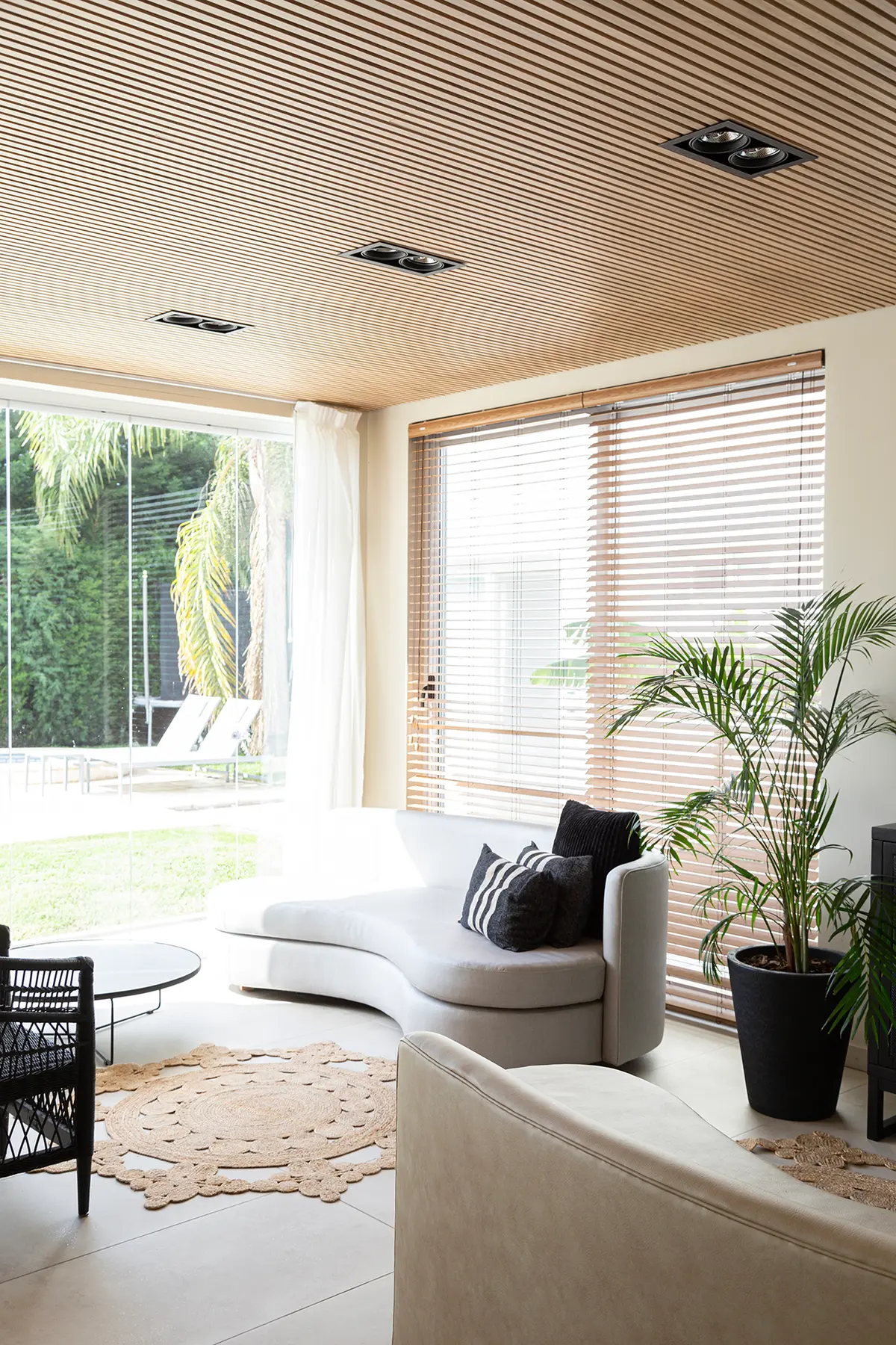 Living moderno con techo de madera, sofá curvo y grandes ventanales al jardín — proyecto Proyecto Gaby P. , por LINEA NETA diseño interior , en Canning