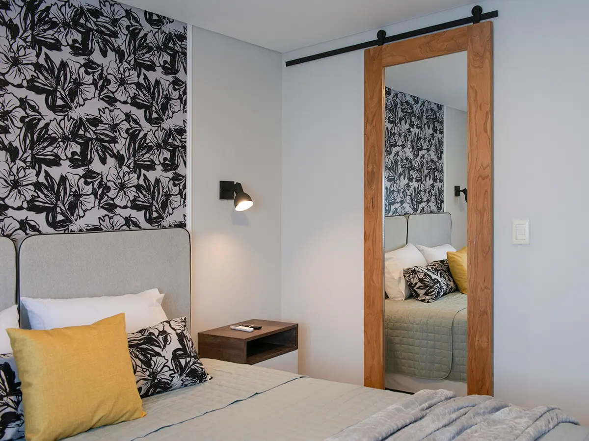 dormitorio moderno con papel mural floral y puerta corrediza de espejo — proyecto Alto Panorama, por Interiores a la carta, en Córdoba