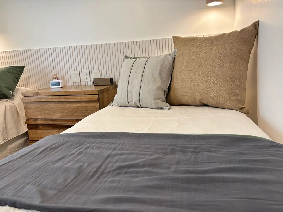 Quarto com duas camas, paredes de madeira e detalhes em bege — projeto Uruguay, por Claraboia, em Recoleta