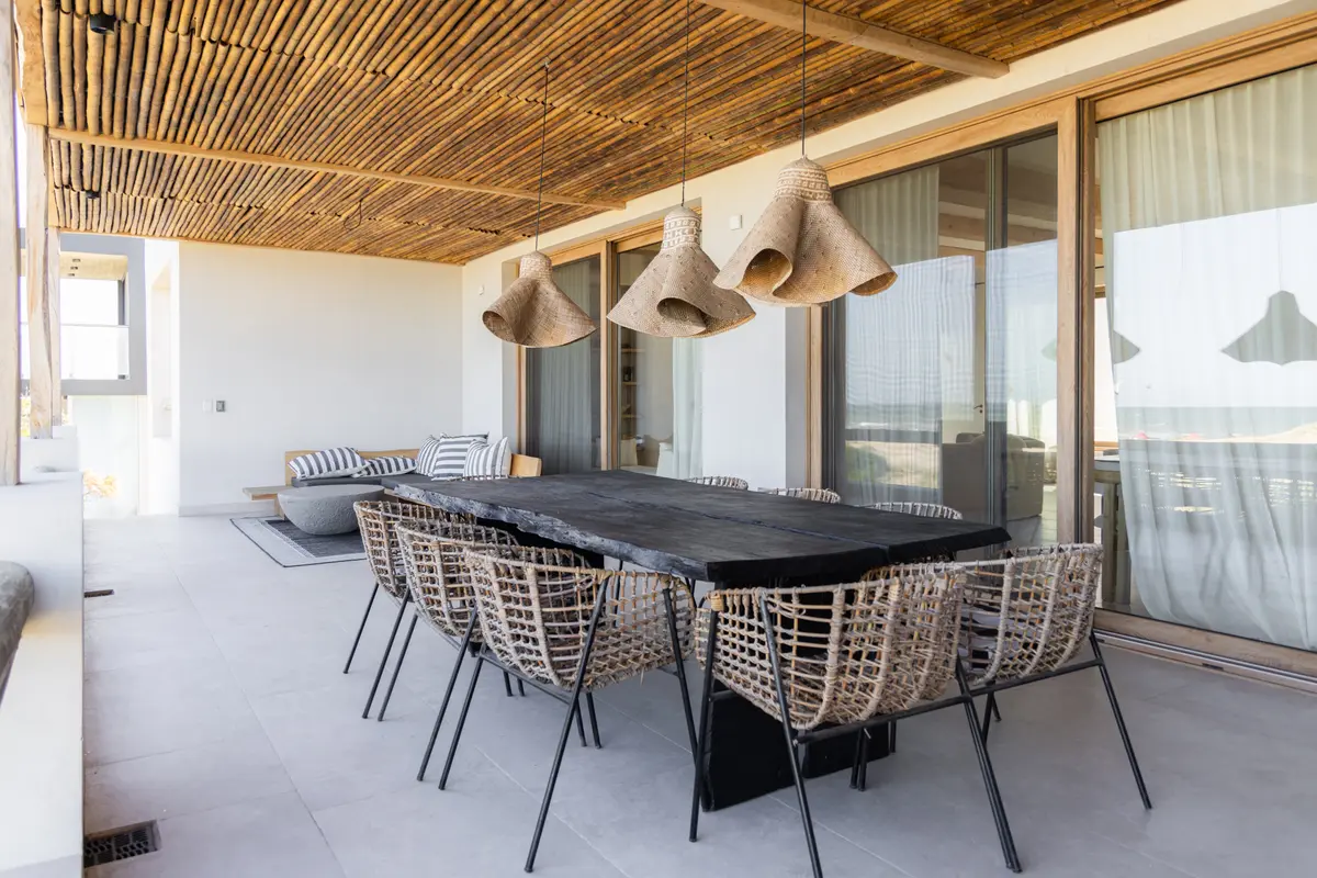 Sala de jantar externa com teto de madeira e móveis de vime — projeto El Refugio, por Grupo Pauta Arquitectura, em Pinamar