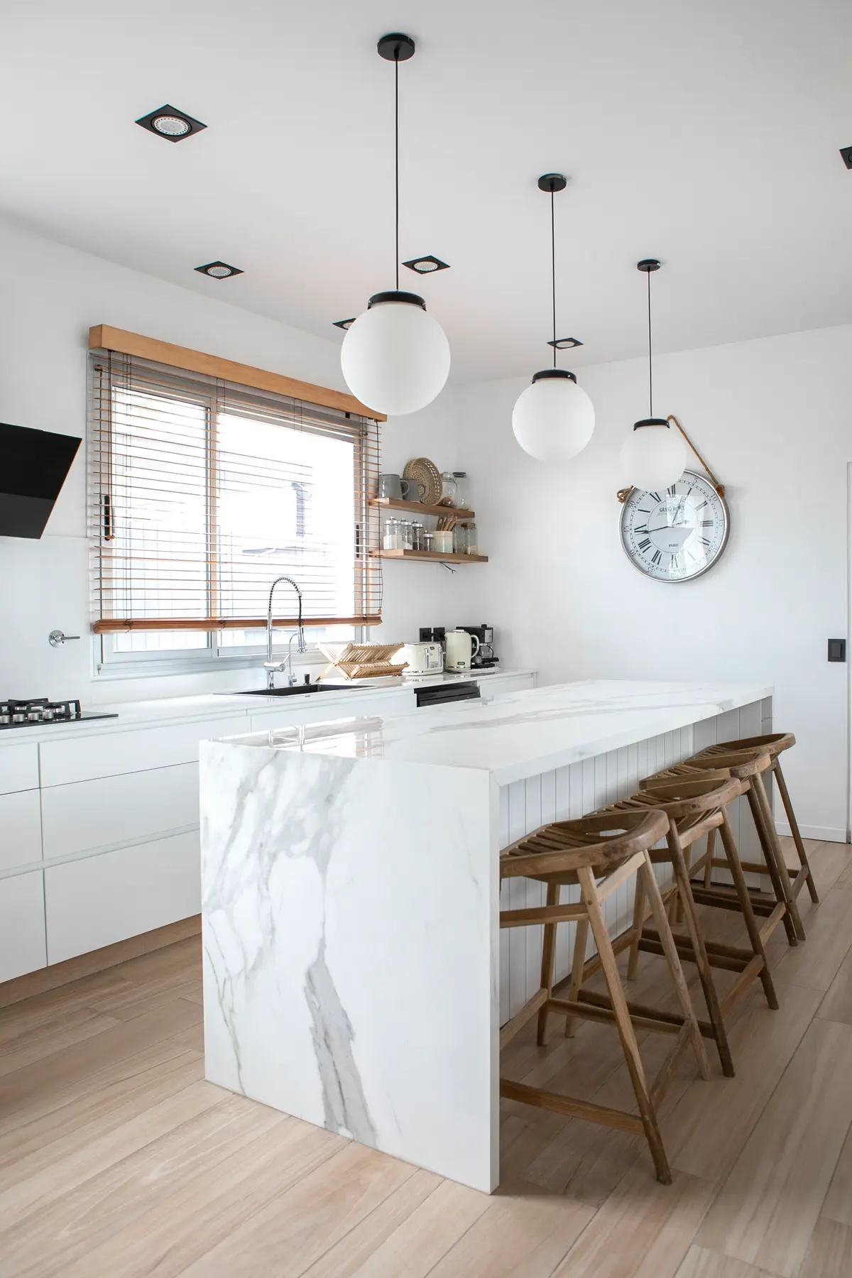 Cozinha moderna escandinava com ilha de mármore e pendentes globulares — projeto Obra El Encuentro, por Arq. Lourdes Yarade Saravia, em Benavidez