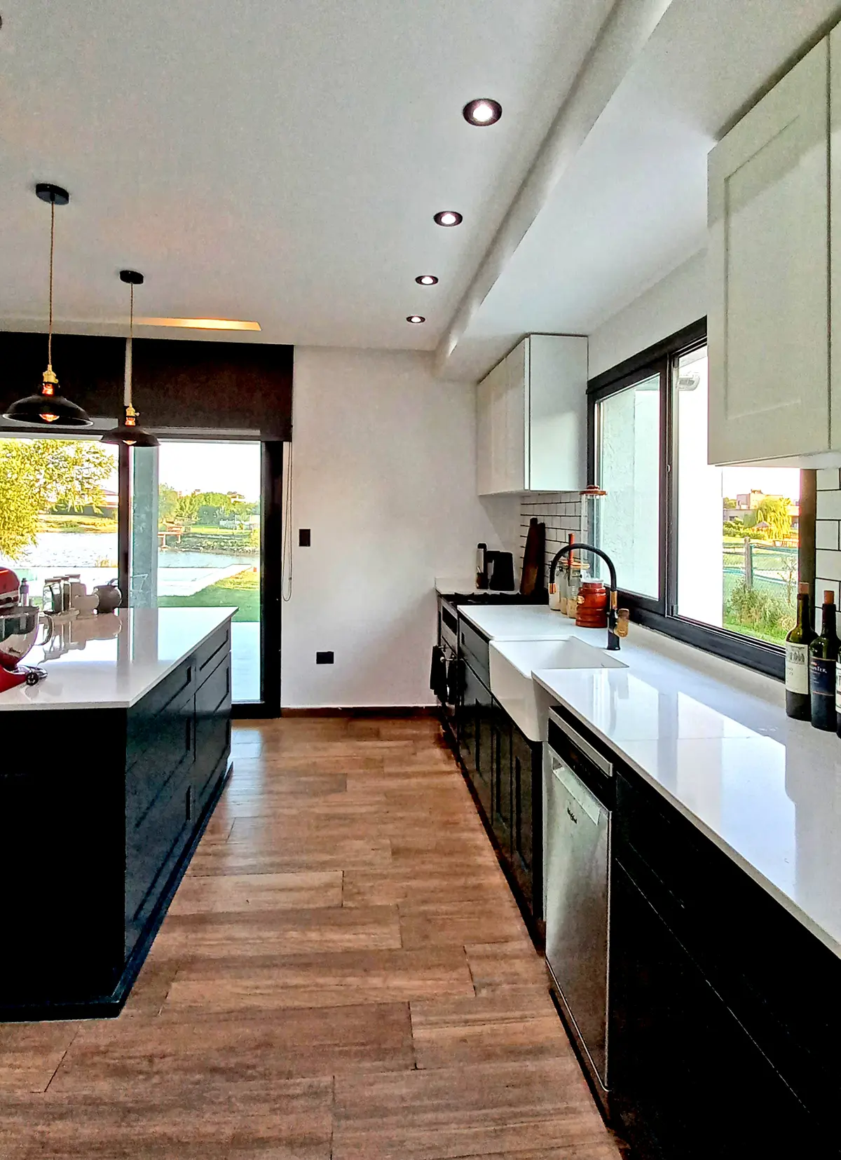 Cocina moderna con isla central, isla negra y ventana grande — proyecto Casa CN451, por EZ architects, en Belén de Escobar