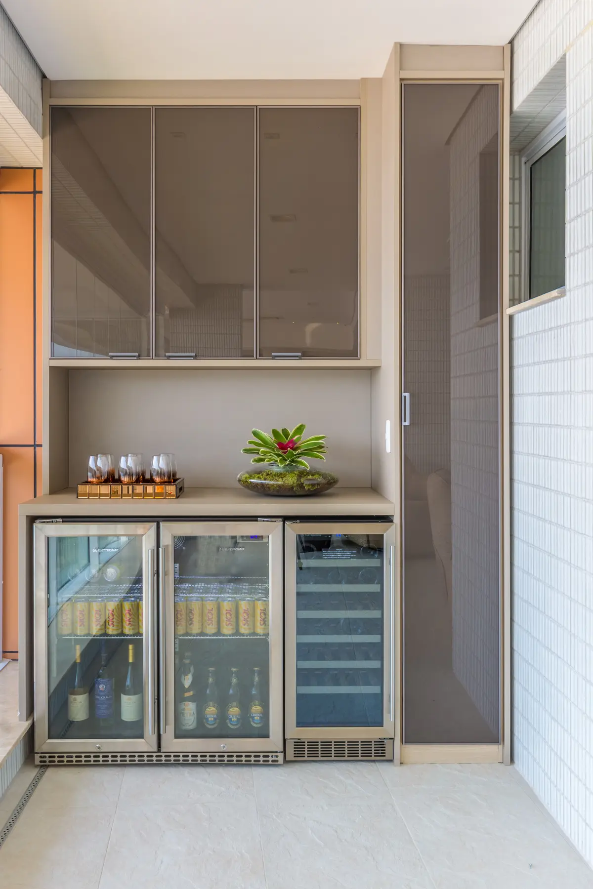 Terraza balcón moderna con bar integrado y heladeras — proyecto Apartamento Riviera, por Patrícia Hagobian Arquitetura e Interiores