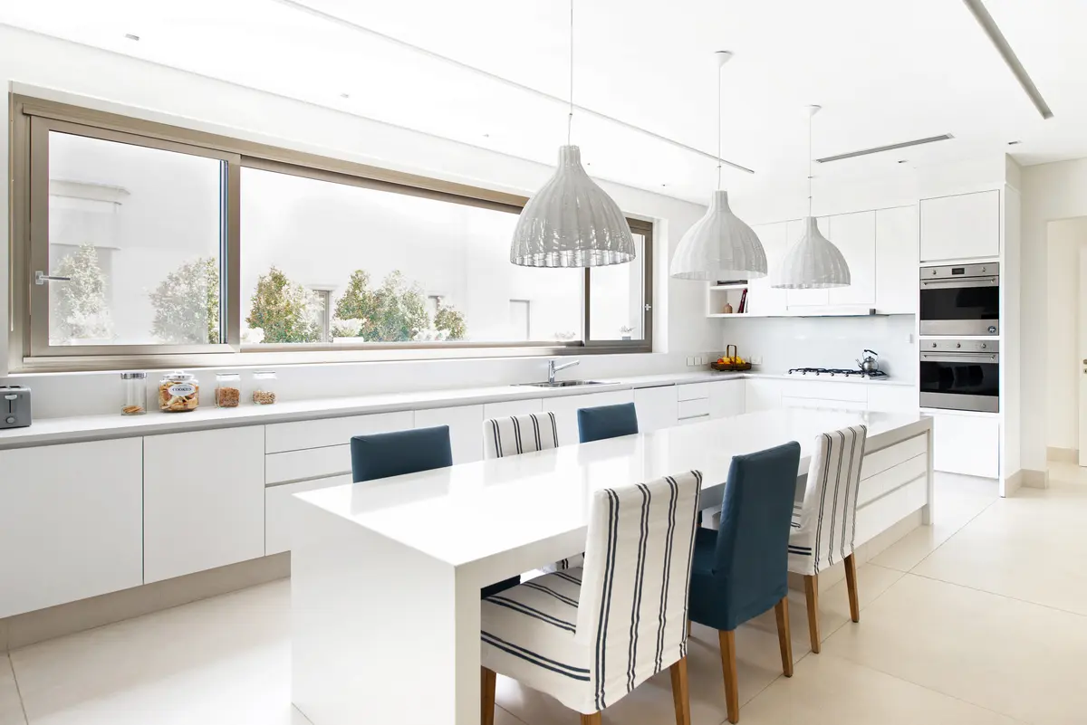Cozinha moderna e aberta com ilha grande, janelas amplas e cadeiras listradas — projeto Casa DF, por Estudio Junor, em Tigre