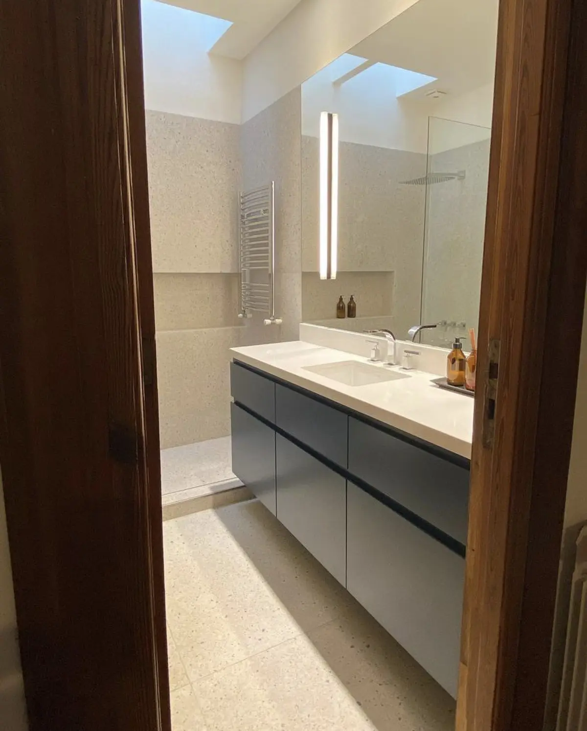 Banheiro moderno com bancada flutuante cinza, cuba integrada e claraboia — projeto Baños Belgrano, por Cudini Estudio, em Belgrano