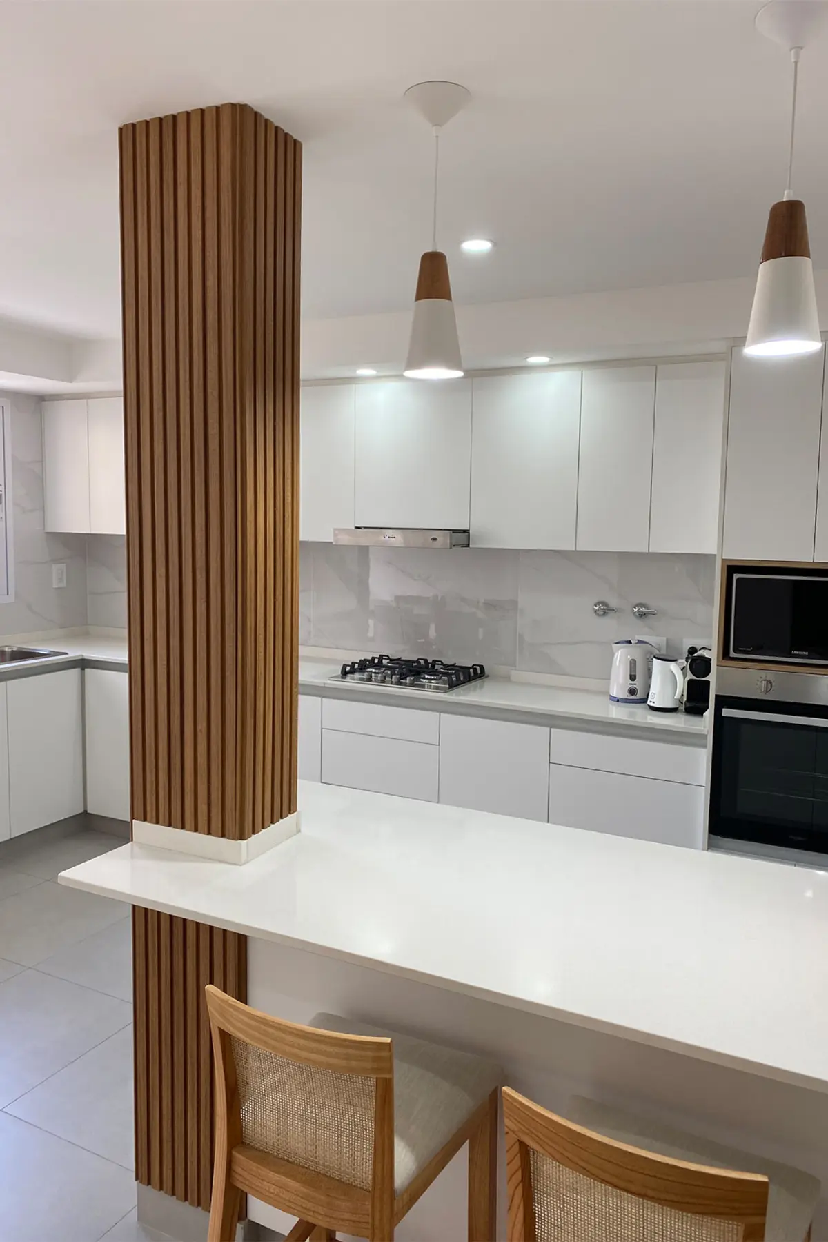 Cocina moderna blanca con isla, columna madera y detalles en tonos cálidos — proyecto COCINA NIEVES, por Estudio Grupo 32, en Buenos Aires