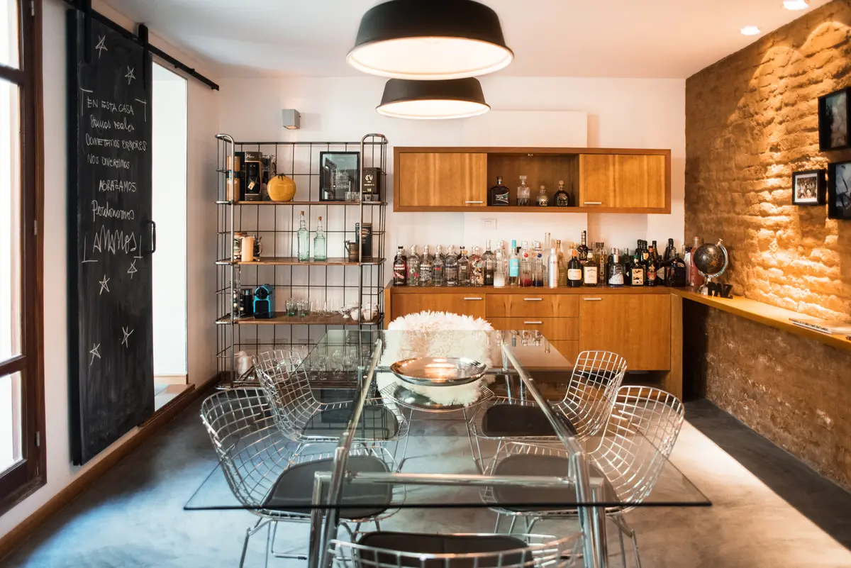 Sala de jantar industrial moderna com mesa de vidro e cadeiras de arame — projeto Defensa, por Estudio Basa, em CABA