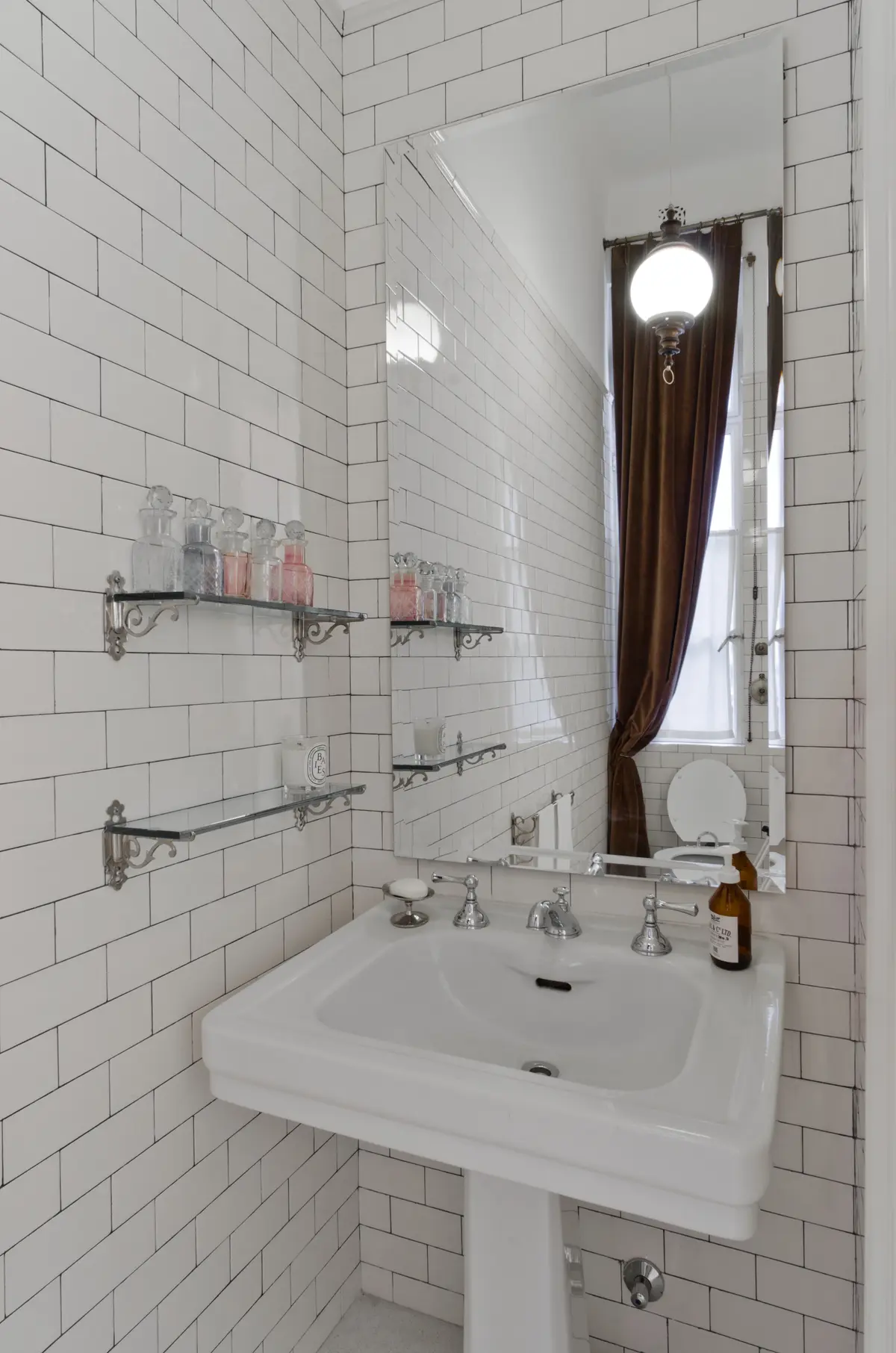 Baño clásico con azulejos blancos, lavabo pedestal y estantes de vidrio — proyecto Dpto LH, por Estudio Dado, en Recoleta