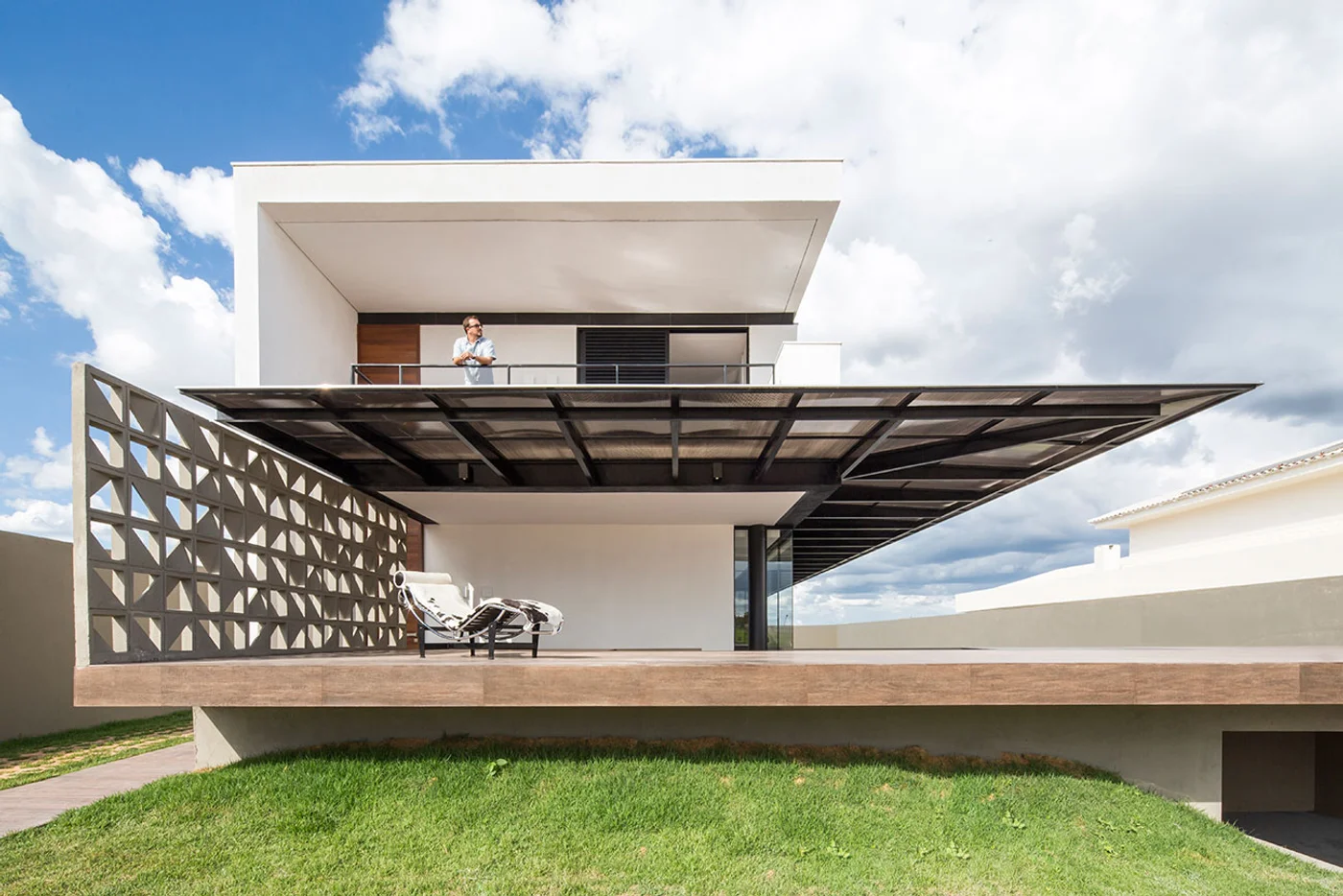 Casa moderna con fachada geométrica y pérgola metálica.