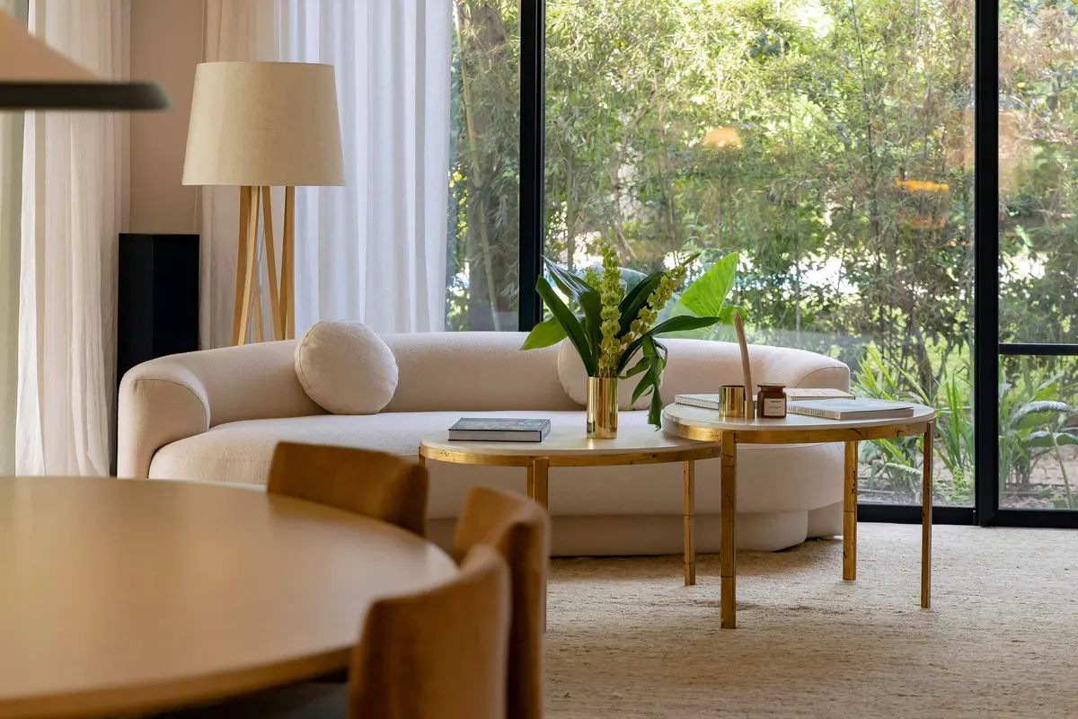 Sala de estar moderna com sofá curvo e vista para floresta — projeto Las Marías, por Santiago Cordeyro Arquitectos, em San Isidro