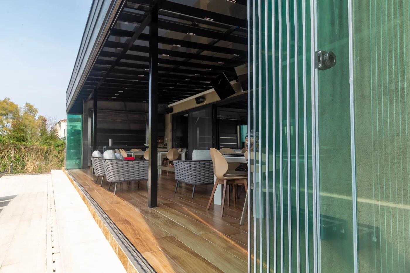 comedor exterior moderno con mesas de madera y sillas de ratán