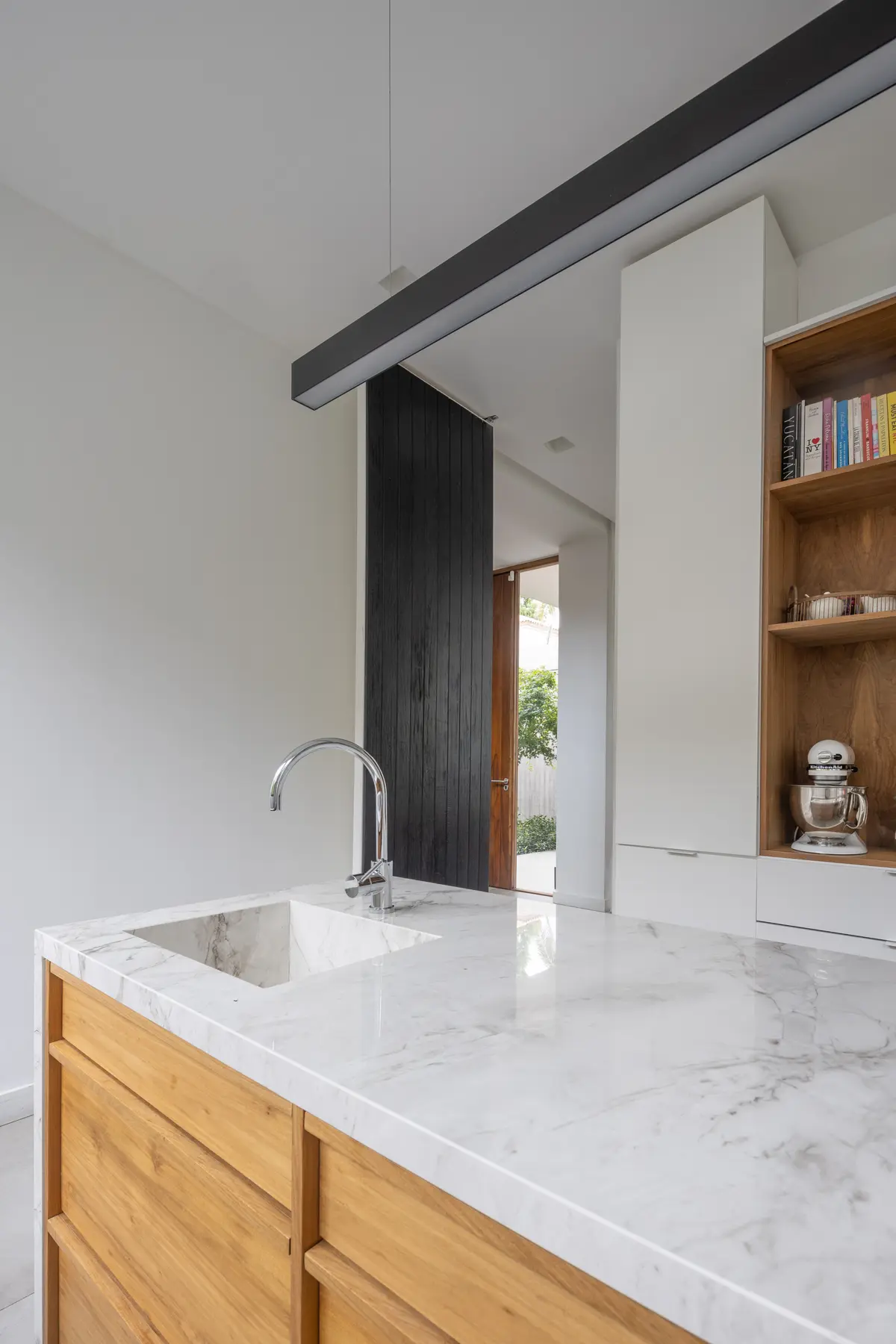 Cocina moderna con isla de mármol, madera y panel de listones oscuros — proyecto CASA OrAz, por Alfredo Orfila arquitectura, en San Isidro