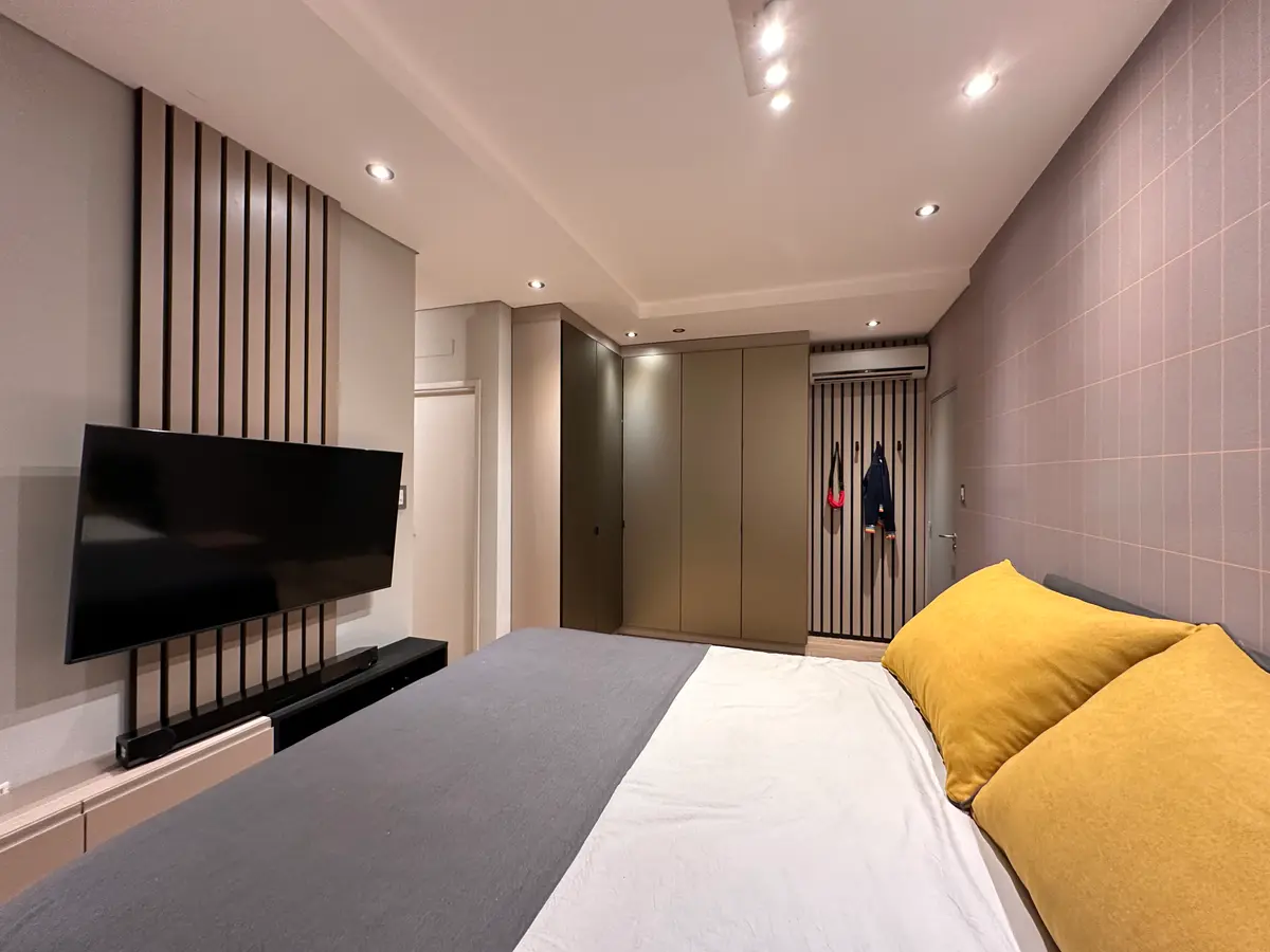 Dormitorio moderno con pared de listones de madera y muebles integrados — proyecto Proyecto saona, por MÁS studio de diseño, en Buenos Aires