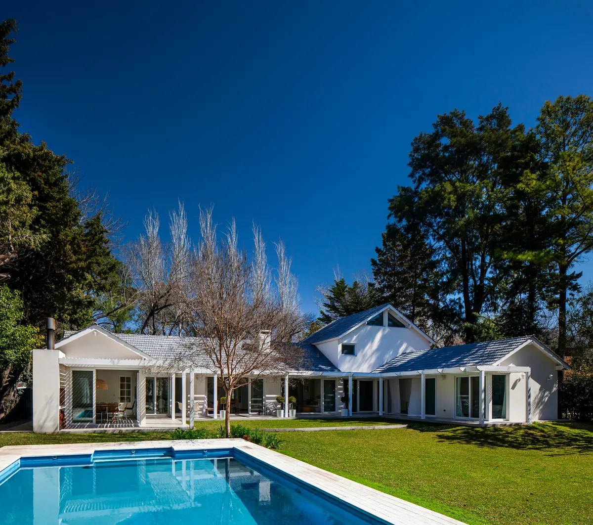 Casa moderna con piscina expansiva y vegetación exuberante — proyecto Highland, por Lala Loviscek arquitecta, en Pilar