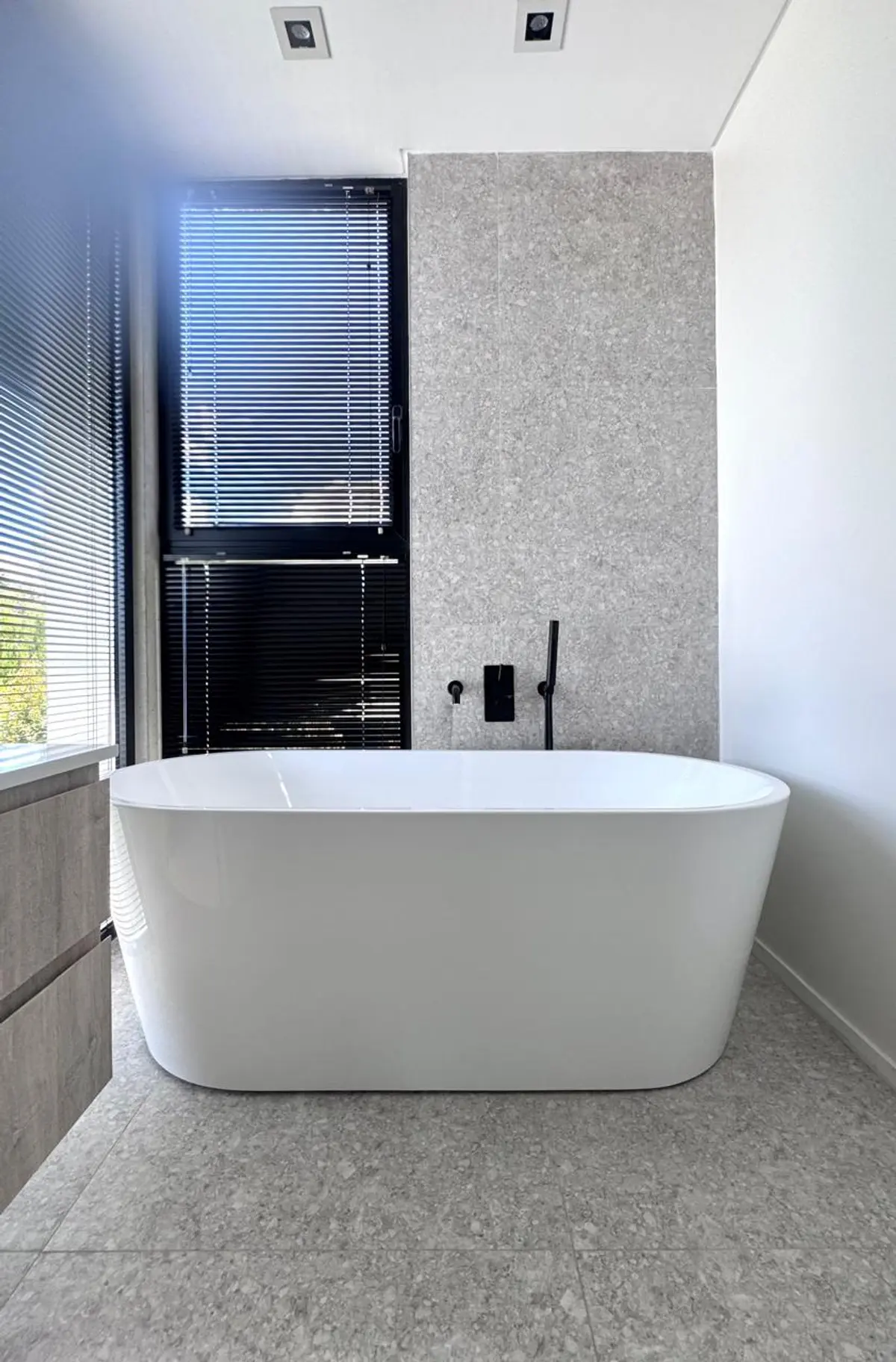 Banheiro moderno minimalista com banheira freestanding branca e paredes de pedra cinza — projeto DISEÑO INTERIOR - SAN BENITO - BAÑO SUITE, por FOCO_arquitectura&diseñointerior, em