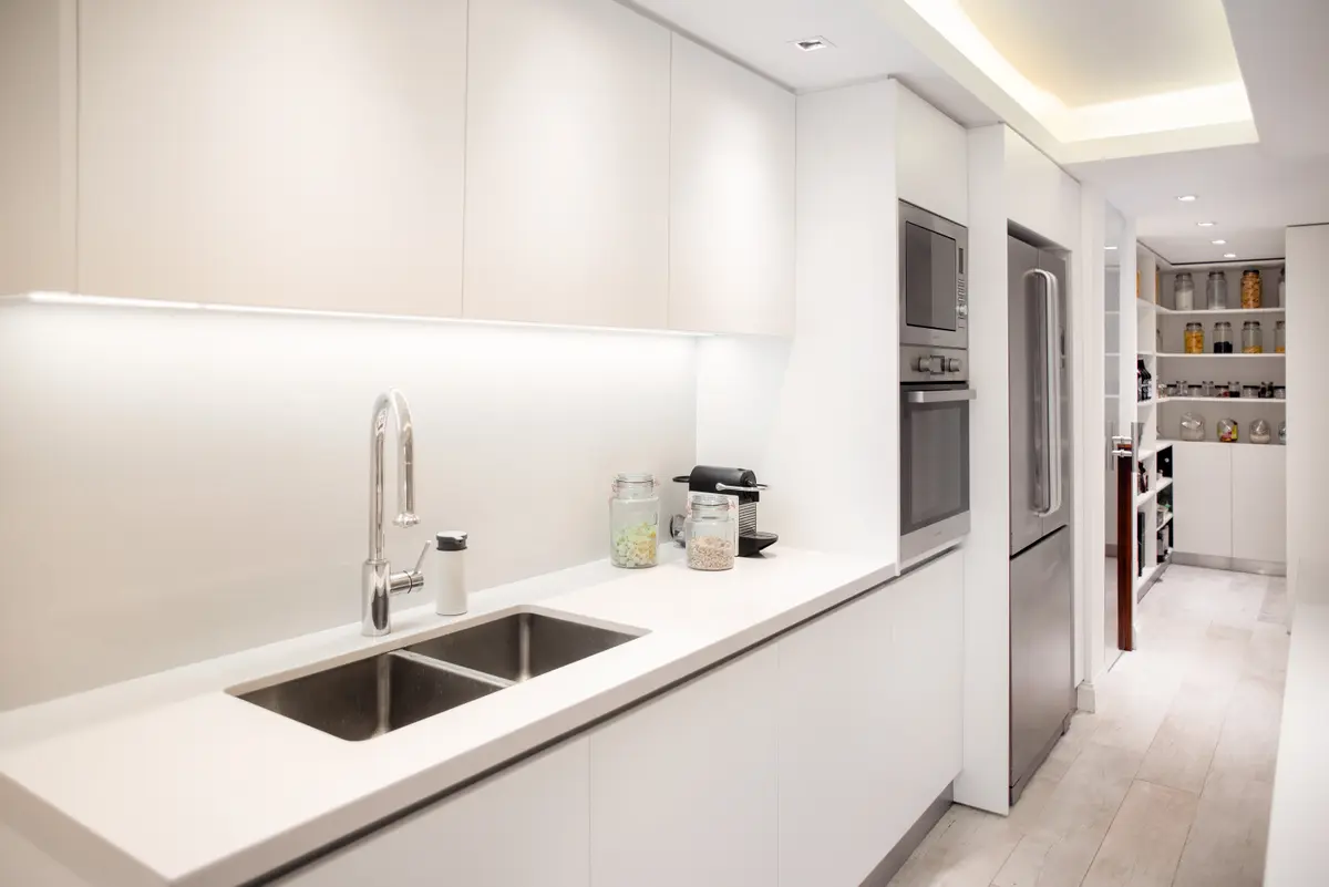 Cocina minimalista moderna con muebles blancos y mesada de piedra — proyecto Libertador , por Estudio Basa, en CABA