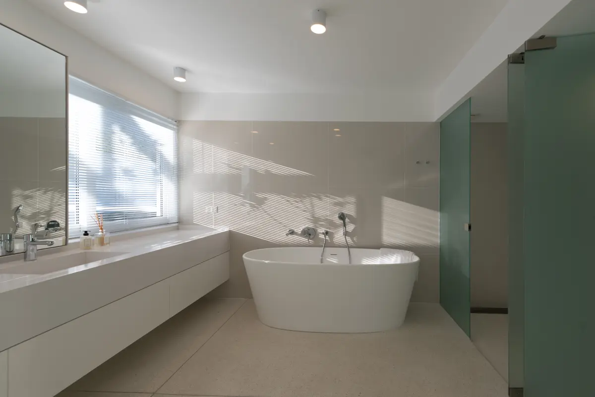 Banheiro moderno minimalista com banheira de imersão e revestimento bege — projeto OX8 - Casa en Martindale, por MLS Estudio, em Martindale Country Club