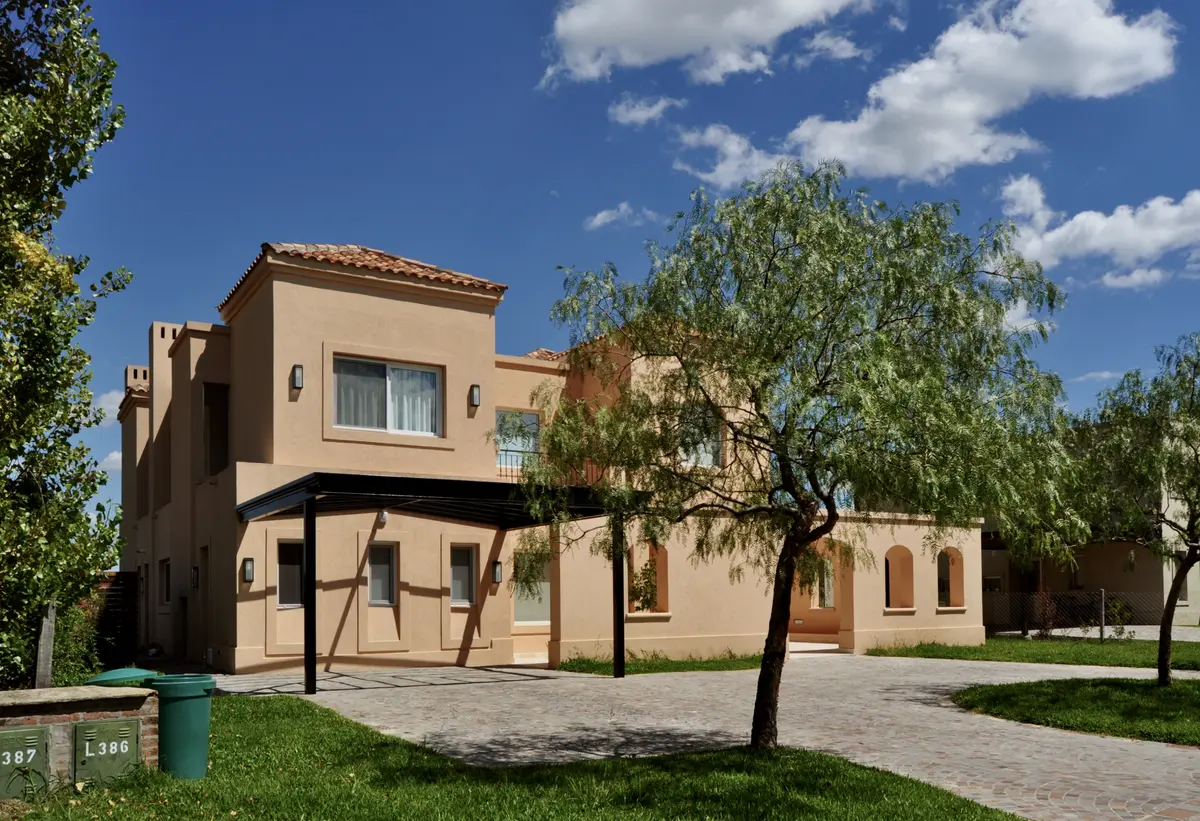 Casa moderna beige con ventanales y pérgola de madera — proyecto Santa Catalina, Villanueva, por Marconi Silva Arquitectos, en Benavidez