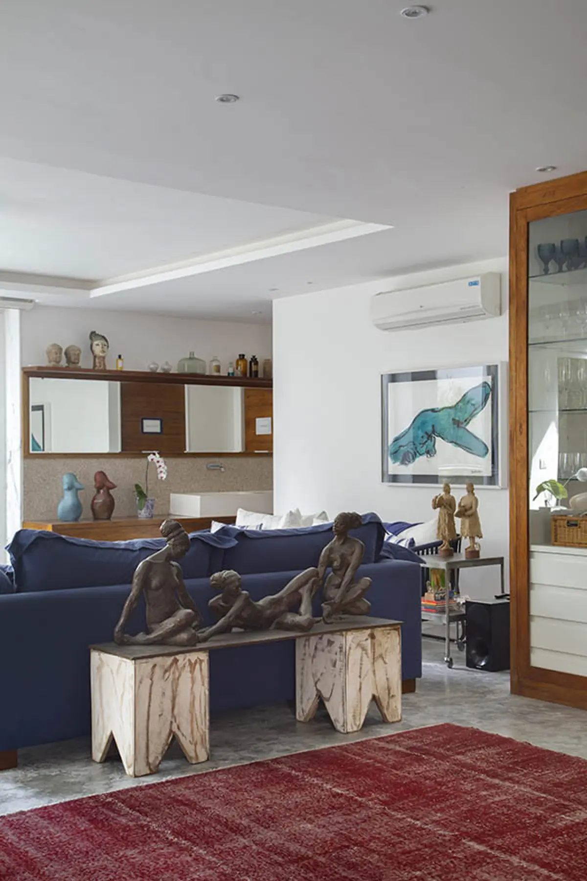 living moderno con sofá azul, esculturas y techo doble altura — proyecto Casa Jardim Guanabara, por Amanda Miranda