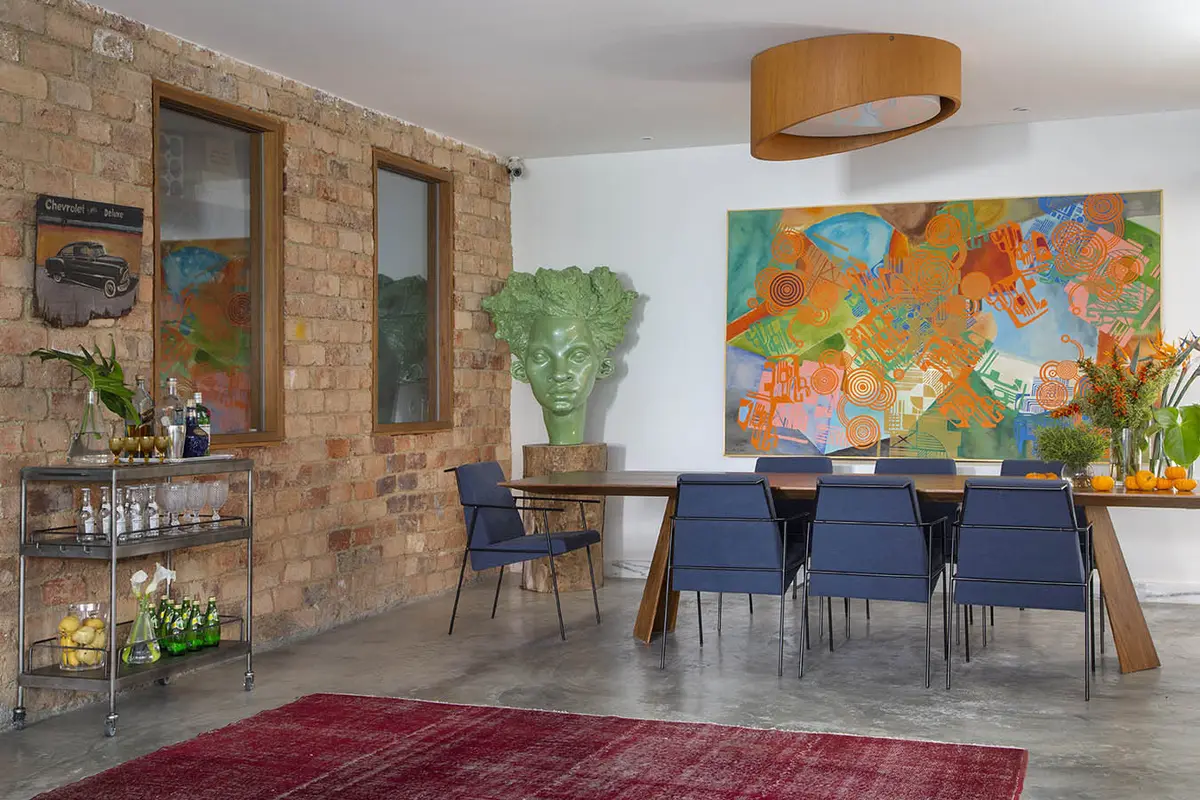 Comedor moderno con pared de ladrillo visto y sillas azules — proyecto Casa Jardim Guanabara, por Amanda Miranda