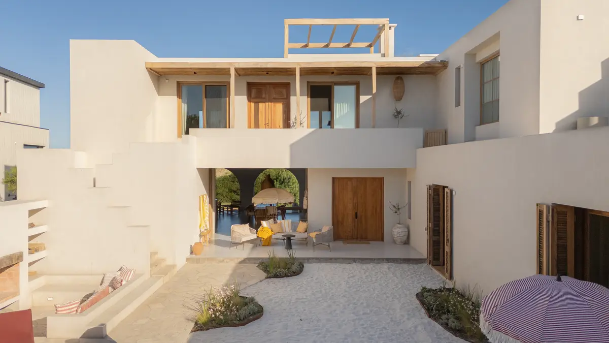 Casa mediterrânea branca com pátio central e detalhes em madeira — projeto El Refugio, por Grupo Pauta Arquitectura, em Pinamar