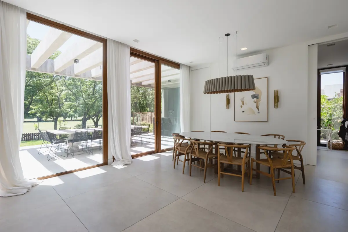 Sala de jantar moderna interna-externa com mesa oval e pergolado — projeto Casa BaCa, por Pedro Busso Arq, em Benavidez