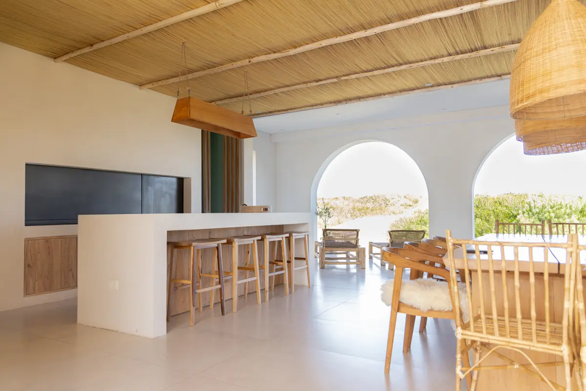 Cozinha e sala de jantar semi-exterior mediterrânea com teto de junco e arcos — projeto El Refugio, por Grupo Pauta Arquitectura, em Pinamar