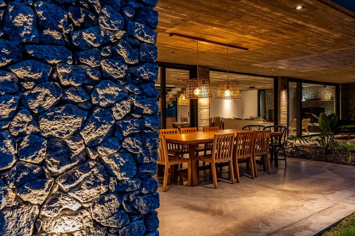 Sala de jantar rústica externa ao lado de muro de pedra com pergolado — projeto casa la huella, por Guerrero Arquitectos, em Pinamar