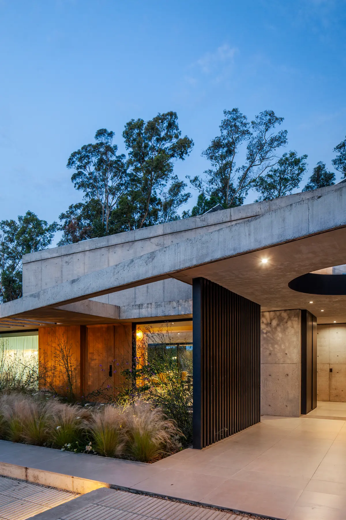 Fachada brutalista moderna com concreto aparente e vegetação integrada — projeto Casa ALVA, por V2 Arquitectos, em City Bell