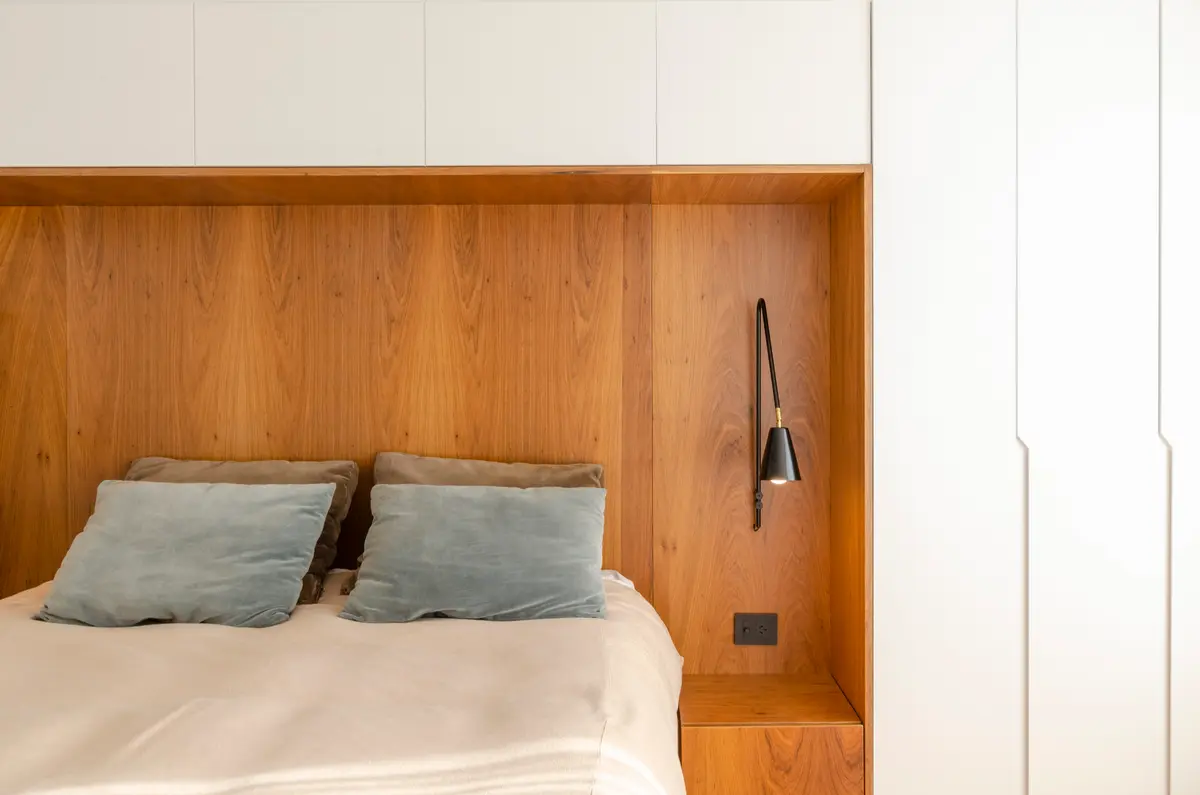 Dormitorio moderno con paneles de madera y luz de pared — proyecto Guayra - Andrea Gonzales, por ABEJA CONCEPT, en Belgrano