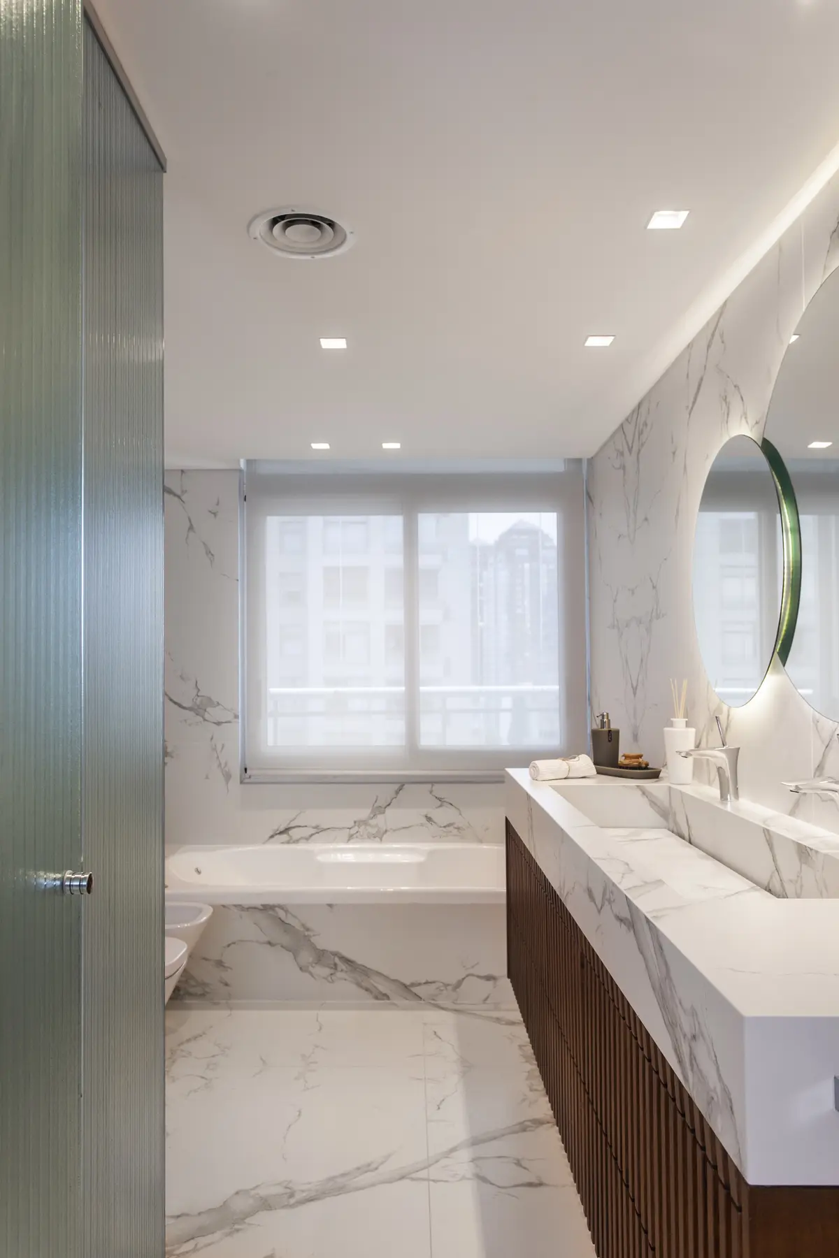 Baño moderno con bañera exenta y revestimiento de mármol — proyecto Pacífico BRT, por Vanguarda Arquitectos, en CABA