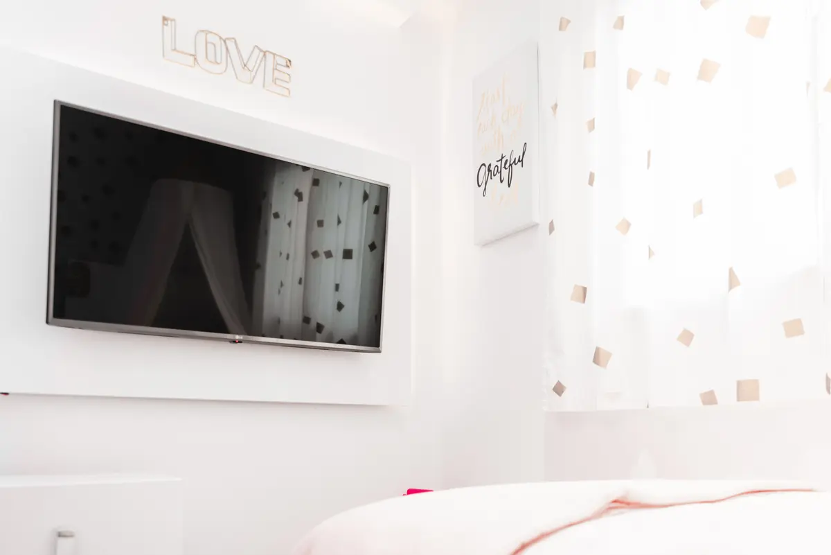 Dormitorio minimalista blanco con TV colgada y detalles decorativos — proyecto Cabrera, por Tali Estudio, en Palermo