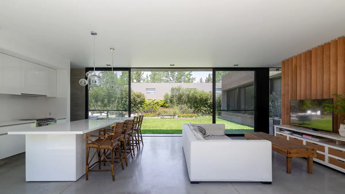 Cozinha e sala moderna com janelões para jardim — projeto Casa LP0405 - Nómade Arquitectura, por Ramiro Sosa Fotografia