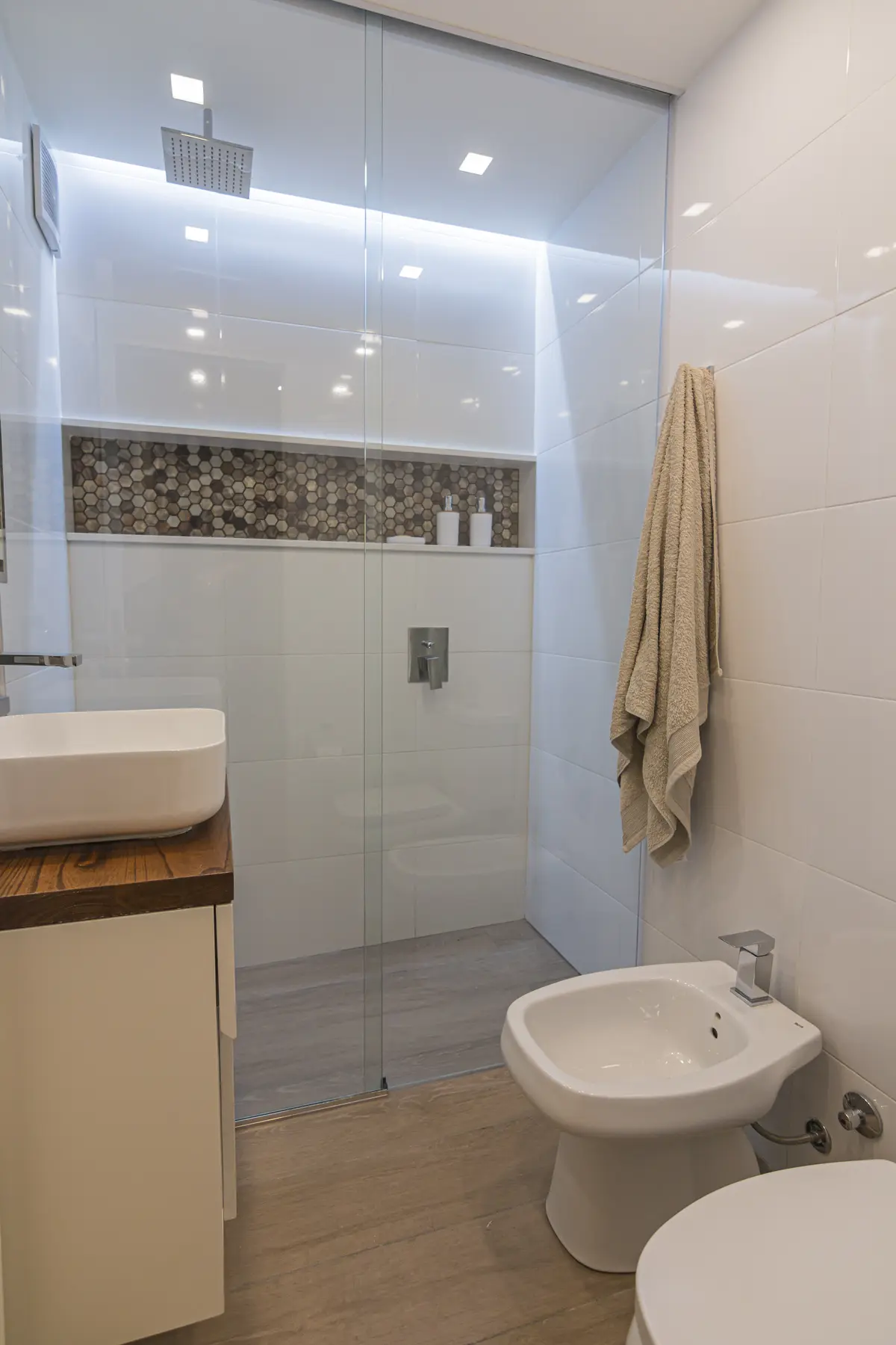 Baño moderno con ducha de cristal, bidet y bacha sobre mueble — proyecto Austria, por ST Arquitectas, en CABA