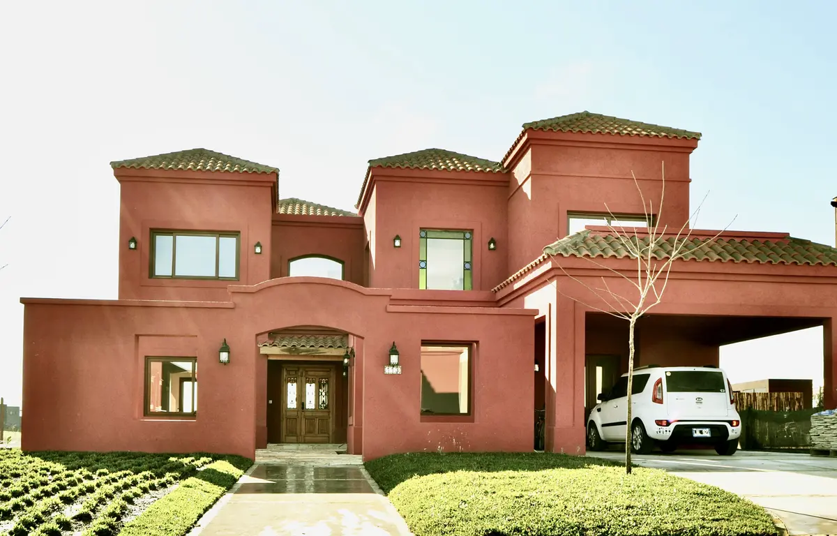 Casa moderna cor terracota com telhado de duas águas e garagem — projeto San Marcos 2, por Marconi Silva Arquitectos, em Benavidez