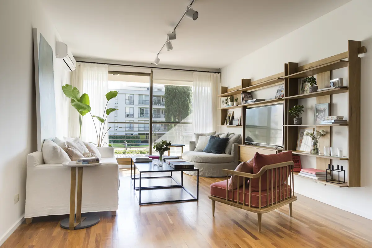 Sala de estar moderna com estante alta e poltrona de vime — projeto Proyecto Don Bosco, por URBANO estudio, em San Isidro