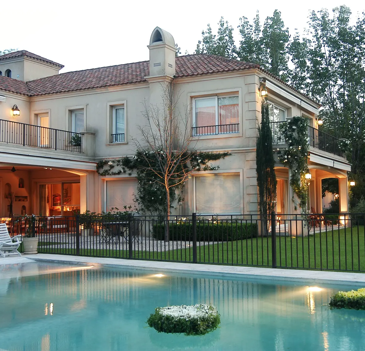 Fachada de villa mediterránea con piscina e jardim ao entardecer — projeto Serena, Provenzal y Mediterránea, por Oppel Arquitectura
