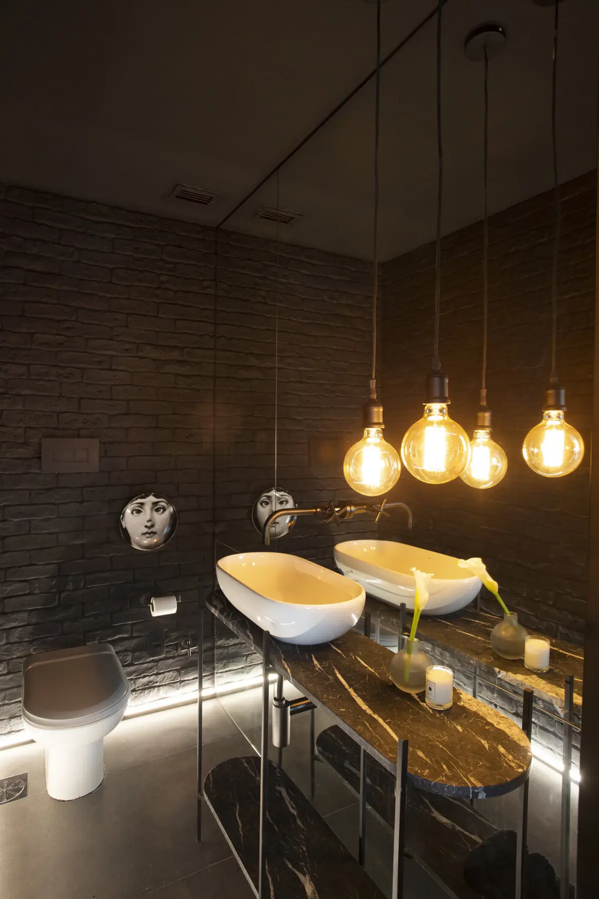 Baño moderno con ladrillo negro, dos lavatorios blancos y lámparas colgantes doradas — proyecto JG House, por Studio Ro-ca