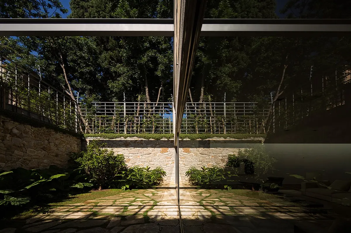 Patio contemporáneo con ventanal, jardinería y luz natural filtrada — proyecto Residência AC, por Gil Fialho