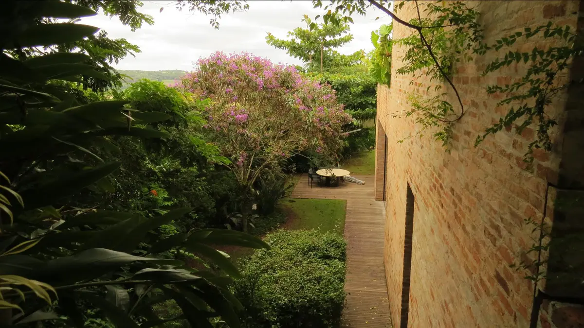 Patio trasero con jardín frondoso y árboles en flor — proyecto Residência MP, por Gil Fialho