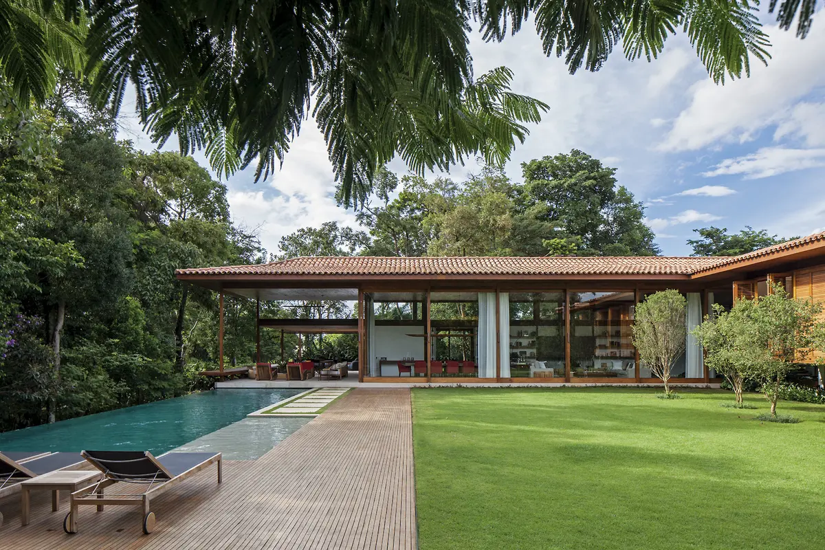 Casa moderna con pileta, deck de madera y jardin impecable rodeado de vegetacion — proyecto Residência GS, por Gil Fialho