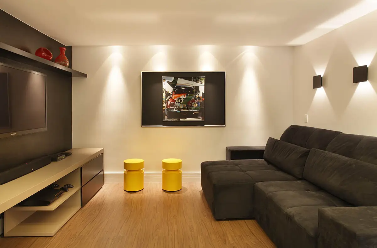 Living minimalista con sofá negro, piso madera y TV de pared — proyecto Casa Barra ED, por Amanda Miranda