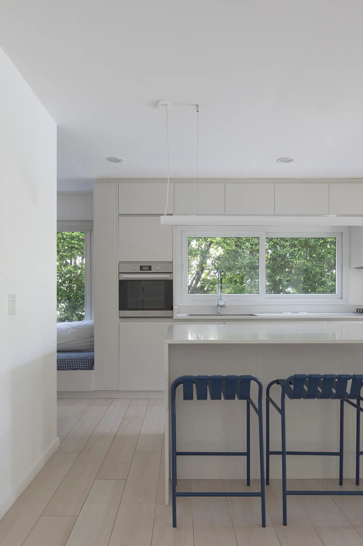 Cozinha escandinava moderna com ilha e banquetas azuis — projeto Reforma Isla del Sol, por Estudio YME, em Rincón de Milberg