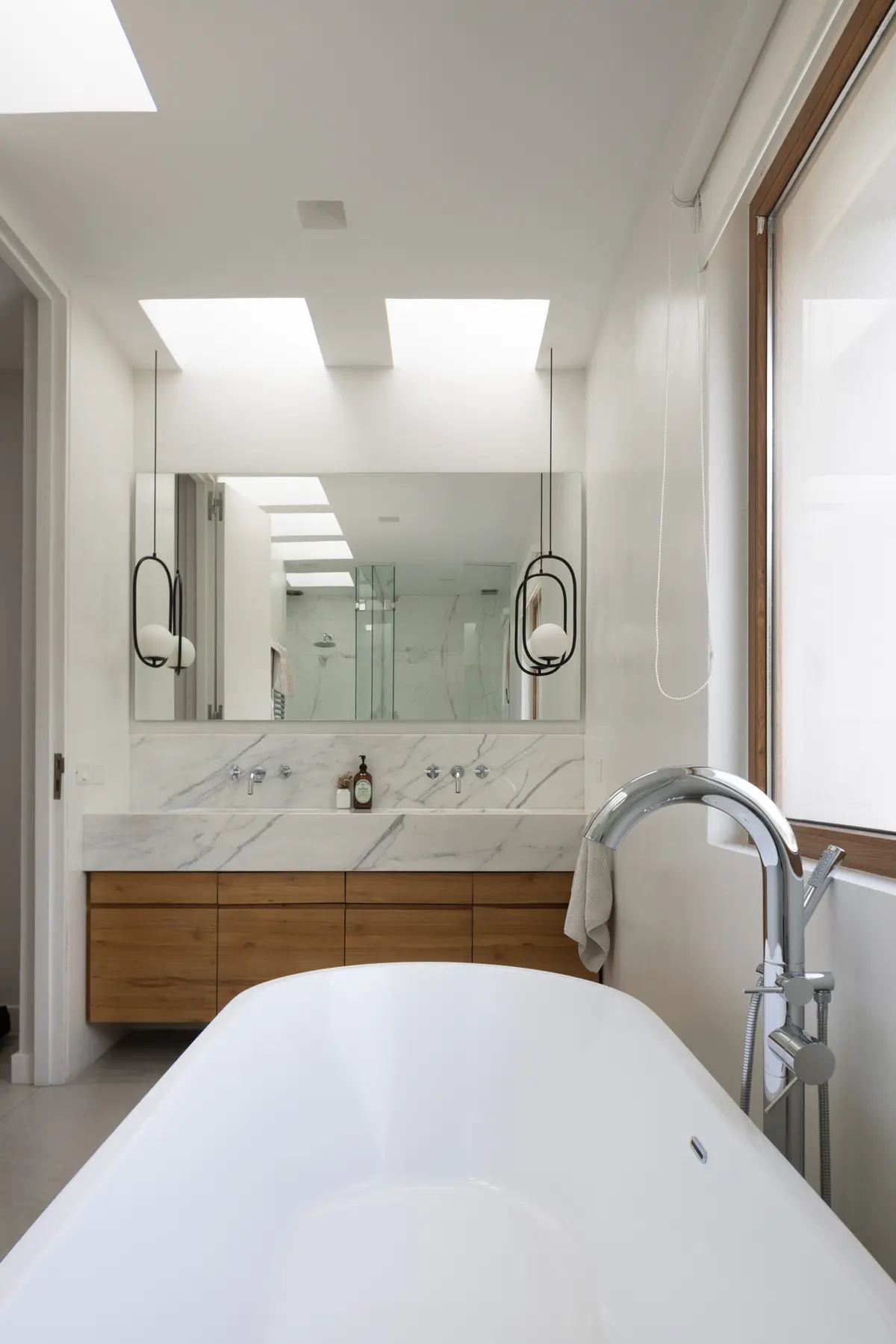 Baño moderno con bañera exenta, doble vanitory y tragaluces — proyecto CASA OrAz, por Alfredo Orfila arquitectura, en San Isidro