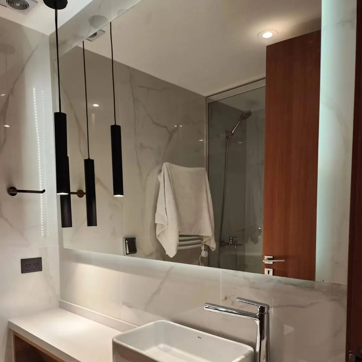Baño moderno con mármol, espejo grande y luces colgantes — proyecto Espejo con bastidor y led, por Cristalcenter, en Recoleta