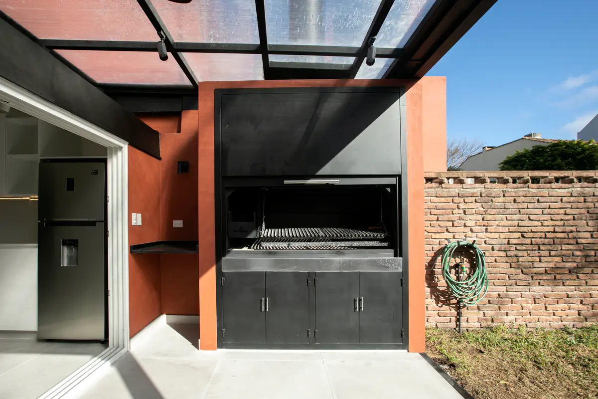 Área gourmet externa moderna com churrasqueira industrial e tijolos — projeto Obra Martinez A, por Arq. Lourdes Yarade Saravia, em Martínez